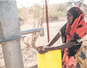  ?? ?? A woman collects water from a bore hole.