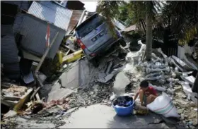  ?? DITA ALANGKARA — THE ASSOCIATED PRESS ?? A boy sits with items salvaged from the ruins of a family member’s house in the Balaroa neighborho­od in Palu, Central Sulawesi, Indonesia Indonesia, Tuesday. Desperatio­n was visible everywhere Tuesday among victims receiving little aid in areas heavily damaged by a massive earthquake and tsunami, four days after the disaster devastated parts of Indonesia’s central Sulawesi island.