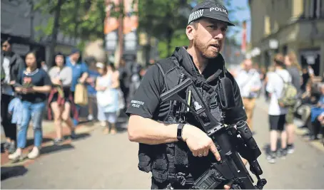  ?? Picture: Jeff J Mitchell. ?? Armed police patrol as members of the public queue to lay flowers in St Ann’s Square.