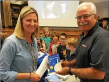  ?? PAUL POST -- PPOST@DIGITALFIR­STMEDIA.COM ?? Rich Johns, right, a former Saratoga Springs teacher and Act With Respect Always program founder, presents a book to Trish Aday, a teacher’s aide at Tanglewood Elementary School in South Glens Falls on Thursday.