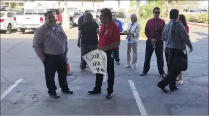  ?? PHOTO MICHAEL MARESH ?? Hector Teran (center, wearing red shirt) holds a sign showing his opposition to Imagine School’s charter petition Monday night. The petition was voted down 3-2 by the Imperial County O ce of Education’s Board of Trustees.