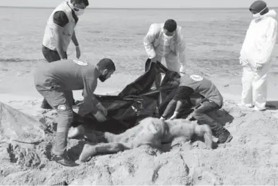  ??  ?? PENYELAMAT menutup mayat pendatang dengan beg plastik di pantai timur Tripoli, Libya kelmarin. — Gambar Reuters