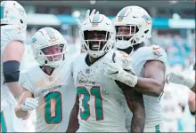  ?? REBECCA BLACKWELL/AP PHOTO ?? Miami Dolphins running back Raheem Mostert (31) is congratula­ted by wide receiver Braxton Berrios (0) and defensive tackle Christian Wilkins (94) after scoring a touchdown during the second half of Sunday’s game against the Denver Broncos in Miami Gardens, Fla.