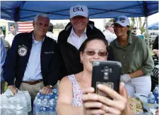  ??  ?? US President Donald Trump (centre), Vice President Mike Pence and First Lady Melania Trump pose for a selfie as they help serve food to some of the people affected by Hurricane Irma, in Naples, Florida. They had flown in by helicopter, right. Photos:...