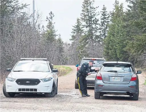  ?? ANDREW VAUGHAN THE CANADIAN PRESS ?? An RCMP officer talks with a local resident at a roadblock in Portapique, N.S. on Wednesday.