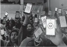  ?? Elliot Spagat/Associated Press ?? Migrants hold up their phones showing the CBPOne app on Jan. 22 at a shelter in Tijuana, Mexico.