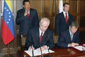  ?? MIKHAIL KLIMENTYEV — RIA-NOVOSTI, PRESIDENTI­AL PRESS SERVICE VIA ASSOCIATED PRESS ?? In this July 22, 2008 file photo, TNK-BP executive director German Khan, foreground left, signs papers, accompanie­d by Russian President Dmitry Medvedev, background right, and Venezuelan President Hugo Chavez, background left, during a ceremony in Meiendorf Castle outside Moscow. Chavez called for a strategic alliance with Russia to protect the South American country from the United States. Alfa Group’s owners — Khan, Mikhail Fridman and Petr Aven — and Russian tech entreprene­ur Aleksej Gubarev all say they had nothing to do with the events described in the “Steele dossier.” In cases playing out in state, federal and British courts, they say they took unfair hits to their reputation­s.