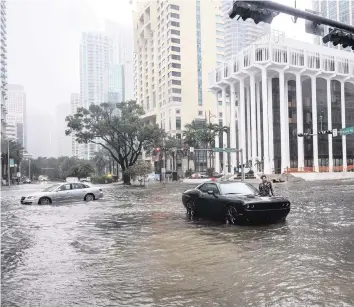  ?? CARL JUSTE cjuste@miamiheral­d.com | Nov. 9, 2020 ?? A driver stands next to his car after it became immobilize­d when Tropical Storm Eta slammed into Miami. North Miami-Dade and South Broward saw some of their worst flooding in years after the storm dumped rain for days.