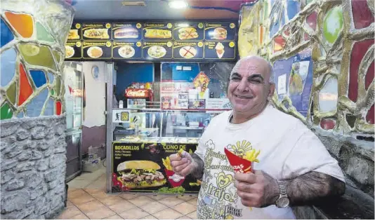  ?? Jordi Cotrina ?? Davood Tiri, el Sultán de las patatas, posa frente a su mostrador del Raval. Debajo, los dispensado­res gratis de mayonesa, kétchup y salsa picante.