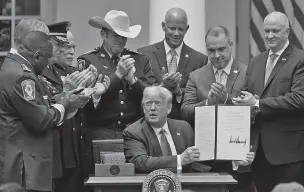  ?? EVAN VUCCI/ASSOCIATED PRESS ?? Law enforcemen­t officials applaud after President Donald Trump signed an executive order on police reform Tuesday at the White House. He devoted most of his remarks at the ceremony to a need to respect and support ‘the brave men and women in blue who police our streets and keep us safe.’