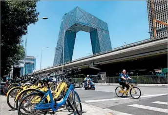  ?? SHIRLEY FENG/WASHINGTON POST ?? A cyclist rides an Ofo bike past other dockless bikes in Beijing, where the low-cost rental service is hugely popular.