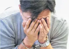  ??  ?? Suspect covers his face after arrested by Thai police in Danok. — Bernama photo