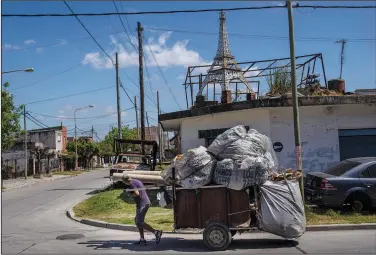  ?? (AP/Rodrigo Abd) ?? A cardboard recycler pulls his cart Oct. 18 past the home of Miguel Munoz, where a replica of the Eiffel Tower stands on a rooftop, elevated on a pile of bricks, in La Tablada, Argentina.