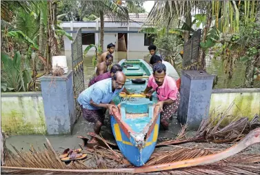  ?? REUTERS ?? People push a boat through the gate of a flooded house at Kuttanad in Alleppey district in Kerala on Friday.