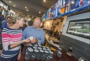  ?? KAZ NOVAK, THE HAMILTON SPECTATOR ?? Laurie Saunders gets a puck signed by Wendel Clark Tuesday in his new restaurant in the Lister Block.