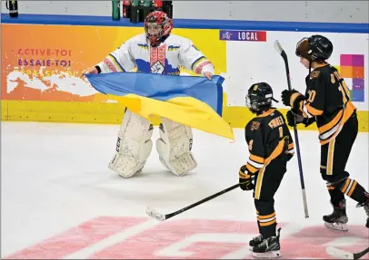  ?? ?? The Canadian Press
The Ukraine Selects team have spent a special time in Canada since the start of the Quebec Peewee Tournament. Ukraine peewee team goalie Dmytro Korzh, (left) celebrates his team’s victory by holding the Ukraine flag as Boston Junior Bruins Patrick Fennell and Brendan O’Toole skate by at the end of the game, Saturday, at Quebec’s internatio­nal peewee tournament in Quebec City.