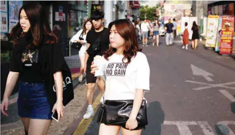  ?? — AFP ?? SEOUL: People walk on a street in Seoul. The South Korean government on July 3 agreed to inject $20 billion into the flagging economy, which has been hit by the MERS virus outbreak and sluggish consumptio­n.