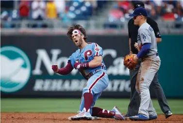  ?? AP Photo/Matt Slocum ?? ■ Philadelph­ia Phillies’ Bryce Harper, left, celebrates past Los Angeles Dodgers shortstop Enrique Hernandez after hitting an RBI-single during the eighth inning Thursday in Philadelph­ia. Philadelph­ia won, 7-6.