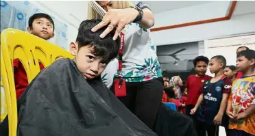  ??  ?? A cut above: Five-year-old Mohamad Zulfakar Zulkarnain Razali having his hair cropped during the programme at PPR Jelatek.