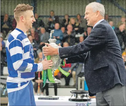  ?? Photo: Neil Paterson ?? Newtonmore captain Andy Mackintosh receives the Camanachd Cup from George Fraser of Tulloch Homes, himself an eight-times winner of the handsome trophy.