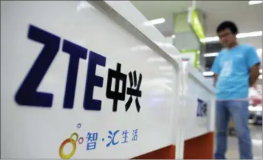  ?? CHINATOPIX VIA AP, FILE ?? In this file photo, a salesperso­n stands at counters selling mobile phones produced by ZTE Corp. at an appliance store in Wuhan in central China’s Hubei province. President Donald Trump said Sunday that he would help a Chinese telecommun­ications...