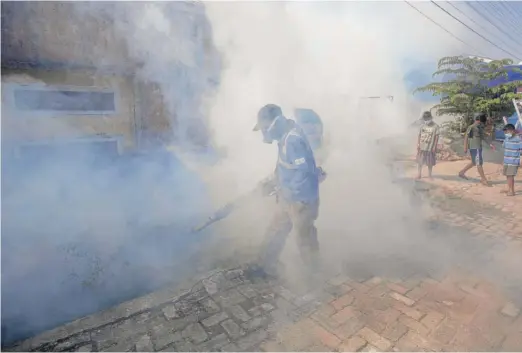  ?? BINSAR BAKKARA/AP FILE ?? A worker fumigates a neighborho­od with anti-mosquito fog to control dengue fever in Medan, North Sumatra, Indonesia, in February.