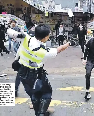  ?? Reuters ?? A still image from a social media video shows a police officer aiming his gun at a protester in Sai Wan Ho, Hong Kong, yesterday