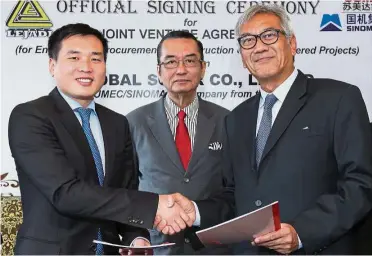  ??  ?? Working together: Li Rongkun (left) exchanging documents with LISB managing director Datuk Sa’id A. Rahman. In the middle is Lim.