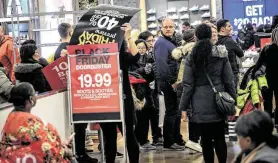  ?? Bebeto Matthews / Associated Press ?? A worker posts signs at a Macy’s in New York on Black Friday, which saw traffic nationwide fall 2.1 percent from 2018, RetailNext preliminar­y figures show.