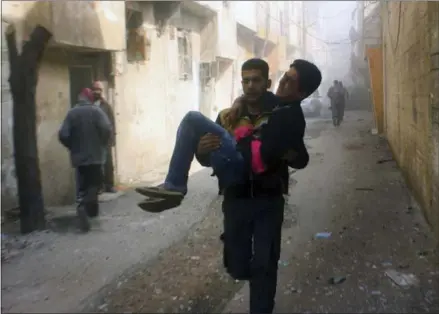  ?? THE ASSOCIATED PRESS ?? A member of the Syrian Civil Defense group carries a young man who was wounded during more airstrikes and shelling by Syrian government forces in Ghouta, a suburb of Damascus, Syria., in this photo released Saturday.