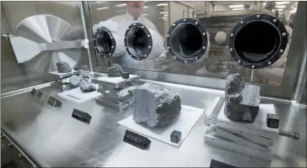  ?? MICHAEL WYKE - THE ASSOCIATED PRESS ?? Ryan Zeigler, Apollo sample curator, left, stands next to a nitrogen-filled case displaying various lunar samples collected during Apollo missions 15, 16 and 17, inside the lunar lab at the NASA Johnson Space Center Monday, June 17, in Houston.