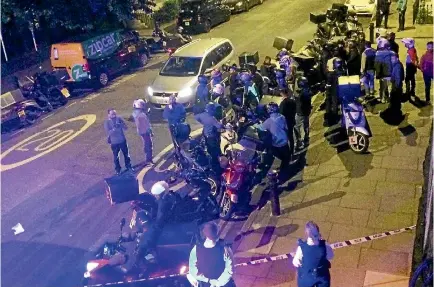  ?? PHOTO: REUTERS ?? Food delivery workers gather after an acid attack at the junction of Hackney and Queensbrid­ge roads, London, at the weekend.