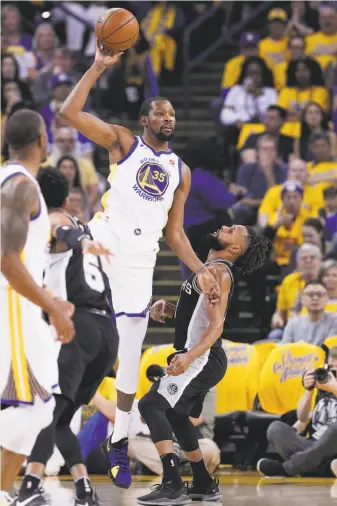  ?? Carlos Avila Gonzalez / The Chronicle ?? The Warriors’ Kevin Durant looks to pass off over the Spurs’ Patty Mills in the first half. Durant is 9 inches taller than Mills, and the height disadvanta­ge was telling throughout the game.