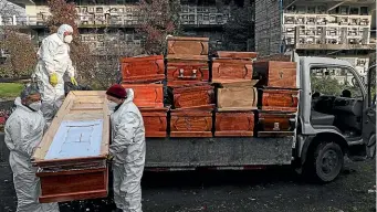  ?? AP ?? Workers collect and stack coffins at the La Recoleta cemetery in Santiago, Chile. The Covid19 virus is spreading rapidly in parts of Latin America.