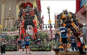  ??  ?? Des statues de Transforme­rs devant un temple bouddhiste, en Thaïlande.