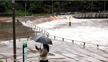  ?? Photo — AFP ?? A woman taking pictures of the overflowin­g Parramatta river at the ferry wharf in Sydney after heavy rain lashed eastern Australia, causing flash flooding and a string of emergency warnings up and down the Pacific coast.