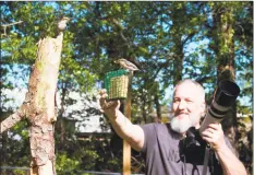  ?? Michael Kopack III / Associated Press ?? Amateur bird watcher Michael Kopack Jr. holds his camera in the background while two nuthatches land nearby. Kopack has gotten deeply involved in bird-watching during the coronaviru­s pandemic and put up a birdhouse for the first time this spring.