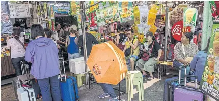  ?? BLOOMBERG ?? Customers, most of whom were tourists, rest in the shade at a drink stall during scorching weather in Bangkok on April 28, as the country braces for higher-thanexpect­ed temperatur­es due to the El Nino weather pattern that is expected to last until June.