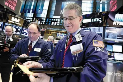  ?? AP/RICHARD DREW ?? Trader Daniel Kryger (right) works Wednesday on the floor of the New York Stock Exchange where stock indexes set new record highs. The Dow Jones industrial average closed above 21,000 points for the first time.