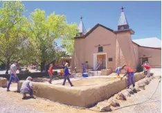  ?? ADOLPHE PIERRE-LOUIS/JOURNAL ?? Volunteers apply adobe to the wall on the grounds of the historic Old San Ysidro Church in Corrales in late April. The Corrales Historical Society is raising money for the upkeep of the church.