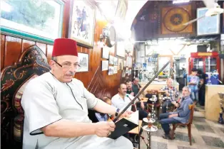  ??  ?? Ahmad Al-Lahham, a Syrian storytelle­r, reads from his storybook in a Damascus coffeehous­e on Monday. (AFP)