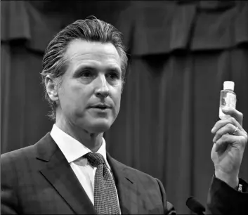  ?? AP PHOTO/RICH PEDRONCELL­I ?? California Gov. Gavin Newsom displays a bottle of hand sanitizer while saying the state would take action against price gouging because of the coronaviru­s, at a Capitol news conference in Sacramento, Calif., on Wednesday.