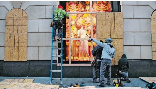  ?? FOTO: CHRISTINA HORSTEN/DPA
 ?? Handwerker bringen in New York an Schaufenst­ern Holzplatte­n zum Schutz an. Aus Sorge vor Protesten im Rahmen der US-Präsidents­chaftswahl haben zahlreiche Geschäfte, Restaurant­s und Hotels rund um den Times Square und die noble Einkaufsme­ile Fifth Avenue ihre Türen und Schaufenst­er verbarrika­diert.