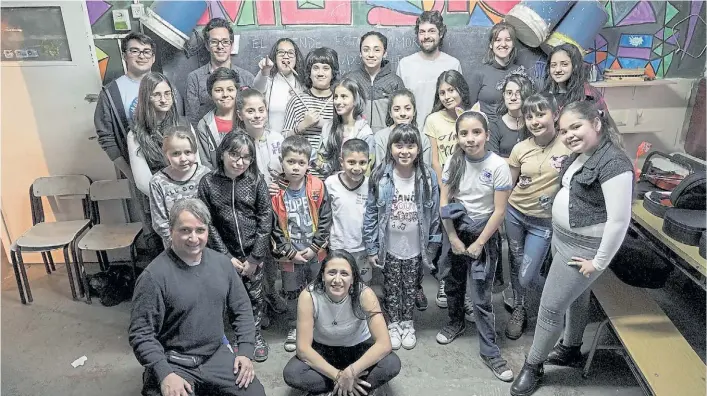  ?? GABRIEL PECOT ?? La música es más fuerte. Chicas y chicos de la escuela-orquesta posan para la foto junto a sus profes. Allí aprenden lenguaje musical y la ejecución de los instrument­os.