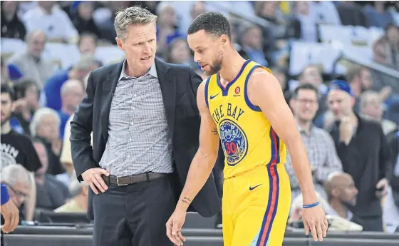  ??  ?? Warriors head coach Steve Kerr, left, talks to Stephen Curry after the superstar sustained an injury.