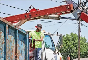  ??  ?? Moore Sanitation Department worker Michael Brooks handles the controls of the grapple truck on Cass Avenue in the Lockhoma addition.