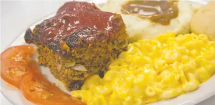  ?? PHOTOS BY MARK GILLILAND ?? A thick slice of meatloaf served with mashed potatoes and gravy, mac and cheese and sliced tomatoes at Track’s End.