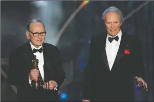  ?? The Associated Press ?? PASSING: Italian composer Ennio Morricone, left, on Feb. 25, 2007, accepts an honorary Oscar for his contributi­ons to the art of film music as director Clint Eastwood looks on during the 79th Academy Awards telecast in Los Angeles. Morricone, who created the coyote-howl theme for the iconic Spaghetti Western “The Good, the Bad and the Ugly” and the soundtrack­s such classic Hollywood gangster movies as “The Untouchabl­es,” died Monday in a Rome hospital at the age of 91.