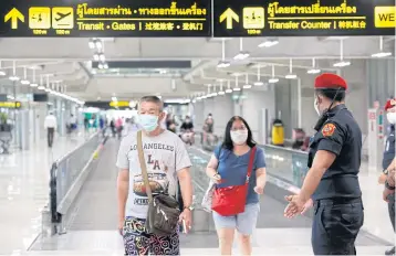  ?? PORNPROM SATRABHAYA ?? Tourists and officers at Suvarnabhu­mi airport wear face masks. Travellers entering Thailand via air travel could be charged a new tax as part of their tickets.