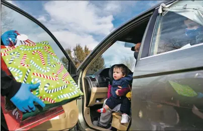  ?? MORGAN TIMMS/Taos News ?? Jose Gonzalez, of Sin Fronteras Nuevo México, hands out presents to a family Sunday (Dec. 20) at the Enos Garcia Elementary School parking lot. “Our motivation is helping the community,” Gonzalez said. “I can relate to them because I know their struggles. My family has been there.”